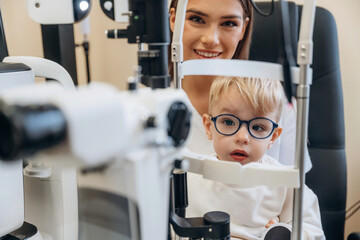 By the modern device. Little boy is having check up in the ophthalmologist cabinet
