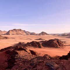 Panoramic desert landscape of Wadi Rum, Jordan. Vast sand plains and dramatic sandstone mountains at sunrise. Natural wilderness scenery