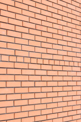 Fototapeta premium Brick wall side view background. Orange brick wall background for exterior design. Construction concept, outdoor buildings, garage or house. Wall with classic checkerboard pattern and visible joints