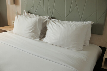 Close-up of a white hotel pillow resting on a neatly made bed, emphasizing comfort and cleanliness