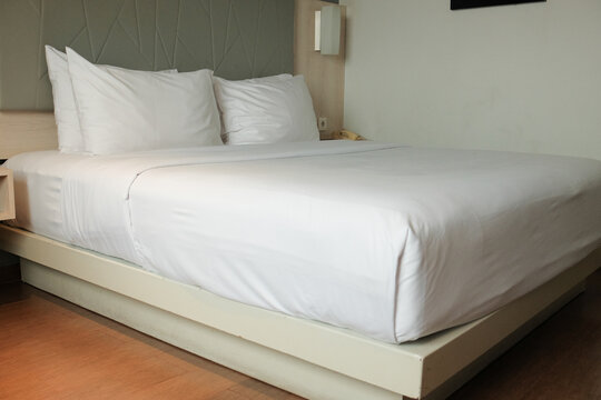 A modern minimalist hotel bed with a sleek design, offering comfort and elegance in a well-arranged room