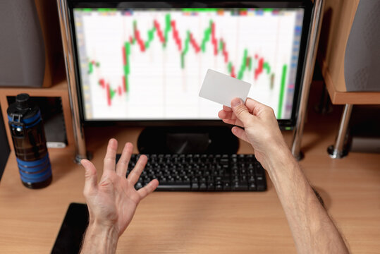 Male excited trader with credit card happy with situation on financial market. Home trader, man analyzing charts on monitor, excited