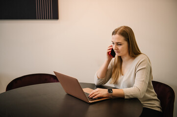 Busy business trader talking on phone. Young stressed analyst woman looking at laptop monitor, feeling tired frustrated reading bad news on financial market working in home office. Trading online.
