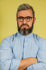 Obraz premium Man with gray beard and glasses stands confidently against yellow background