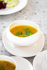 A steaming bowl of vibrant soup garnished with fresh herbs, placed elegantly on a minimalist stone table. Perfect for food styling, culinary themes, or healthy eating concepts
