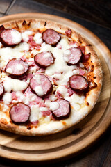 Pizza with sausage, ham and mozzarella cheese on wooden background. Soft focus. Close up	