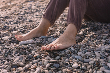 Relaxing by the riverbank with bare feet on smooth pebbles during a sunny afternoon