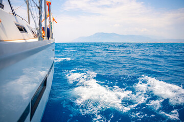 Fototapeta premium Yacht sailing in an open sea. Close-up view of side of the boat. Clear sky after the rain, waves and water splashes