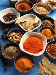 Colorful assortment of spices and herbs on a blue rustic wooden table