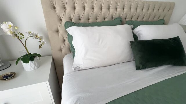 quarto com cabeceira em captone confortavel com cama arrumada em tons verdes e brancos 