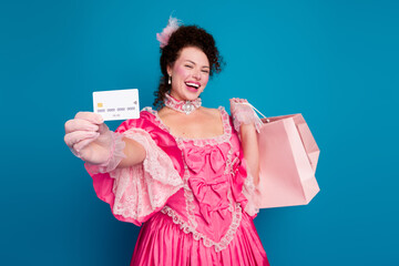Elegant woman in pink baroque dress holding shopping bag and card against blue background