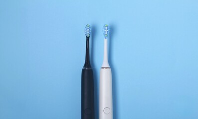 Two electric toothbrushes on a light blue background showcasing modern dental care technology and design features