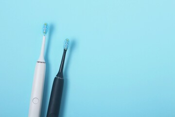 Fototapeta premium Two electric toothbrushes on a light blue background showcasing modern dental hygiene tools for effective oral care