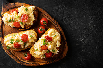 Scrambled eggs with onion and tomatoes on toasts