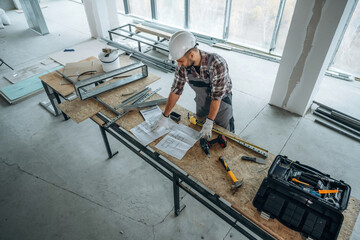 Wooden table with metal foundation. A man is renovating an unfinished room