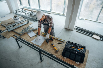 By the table. A man is renovating an unfinished room