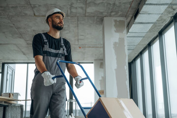 Moving stuff. A man is renovating an unfinished room