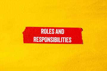 Roles and responsibilities message written on ripped torn red paper tape on yellow background....