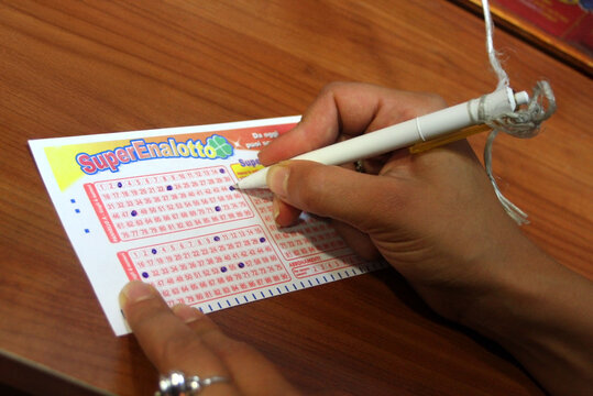 A woman plays the numbers on a SuperEnalotto card, an Italian numerical gambling game with totalizers and prizes, operated by SISAL. Italy lottery