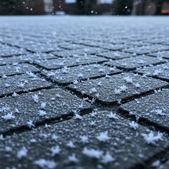 Obraz premium Snowflakes delicately landing on a frozen cobblestone street, forming a natural mosaic.