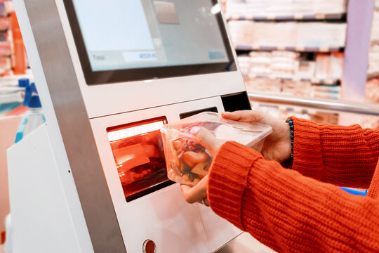 Customer scanning groceries at self checkout kiosk in supermarket