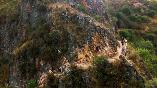 Tourists hiking along a narrow trail near Qhapaq &Ntilde;an and Inkilltambo ruins, Cusco, Peru