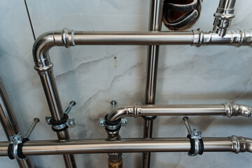 This captivating image features a closeup of polished stainless steel pipes in a modern bathroom, highlighting their sleek, shiny finish that reflects light beautifully