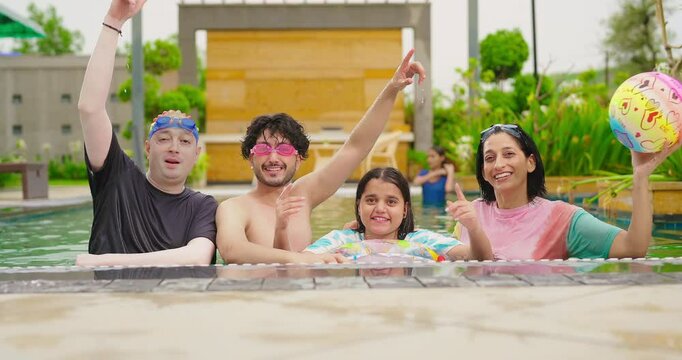 Indian happy family group with teen child dancing look cam enjoy outdoor resort pool edge trip mom dad young adult girl boy make female do pose have fun joy spend day time at outside water park
