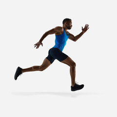 Low angle view of muscular young man with sportive body in motion, running, training isolated on white studio background. Concept of sport, competition, endurance, athletics, marathon