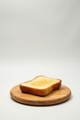 A Single Slice of Golden-Brown Toasted Bread Resting on a Smooth Wooden Board Against a Plain White Background