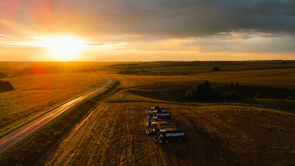 Harvesters are standing in a field at a beautiful sunrise
