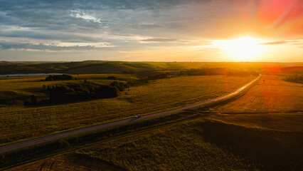 The car is driving along the highway at dawn