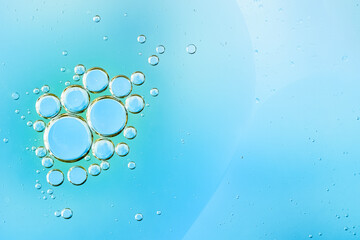 Transparent water bubbles rising in a light blue liquid background. Refreshing, clean photo perfect for themes of purity, hydration, freshness. Macro of hyaluronic acid, facial moisturizer. Copy space