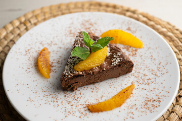 Delicious piece of chocolate cake with fresh orange pieces.