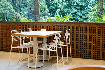 A white table in a café setting with an outdoor background featuring lush green trees, creating a fresh and relaxing atmosphere