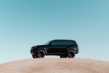 Obraz premium majestic suv parked atop scenic hill under clear blue sky perfect for showcasing its sleek design against nature backdrop