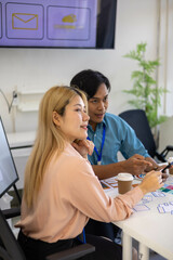 Three people are sitting around a table, working on a project. They are wearing name tags and are pointing at a whiteboard. Scene is collaborative and focused
