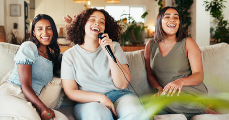 Karaoke, friends and women singing on living room sofa with microphone for music, playlist or...