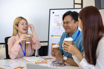Three people are sitting around a table, working on a project. They are wearing name tags and are pointing at a whiteboard. Scene is collaborative and focused
