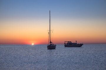 Fototapeta premium Breathtaking Sunrise Over Cala Joncols With Tranquil Boats in Costa Brava Waters, Roses, Catalonia