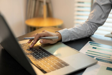 A man is sitting at a desk with a calculator and a stack of papers. He is focused on the numbers on the papers and he is working on some financial calculations
