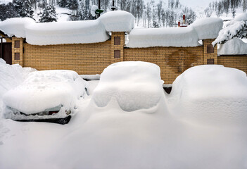 Cars covered with snow in the parking lot in rural mountain area