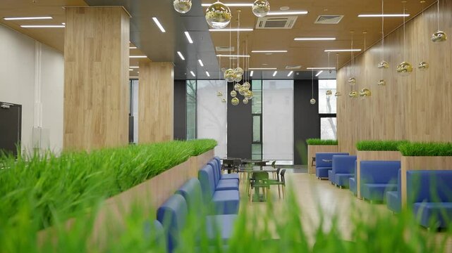 Panoramic shot of empty cafeteria. Large canteen with grass decoration and panoramic windows.