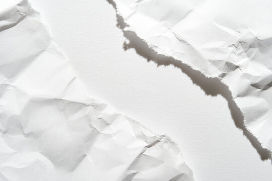Close-up of torn white paper with rough edges and textured surface creating abstract composition.