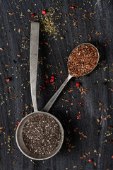 Old spoons with chia and flax seeds on black background. Flat lay. Top view. Food concept. Dark mood food photography.