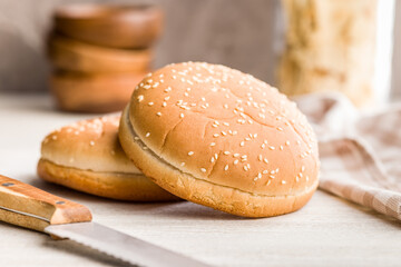 Empty burger bun with sesame seeds on kitchen table.