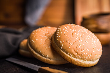 Empty burger bun with sesame seeds on black table.