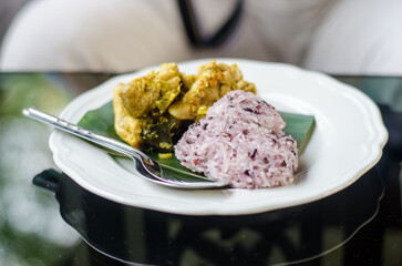 sticky purple rice and chicken on the white dish on the table