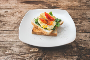 Breakfast sandwich with egg, watercress and tomato on the wooden table, healthy food