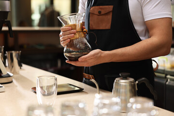 Barista with glass coffeemaker at table in cafe, closeup